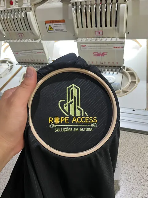 Logo de empresa sendo bordada em jaqueta, ainda no bastidor